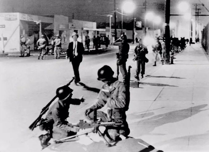 California National Guardsmen take up positions a street in the Watts section of Los Angeles during race riots. Aug. 14, 1965.