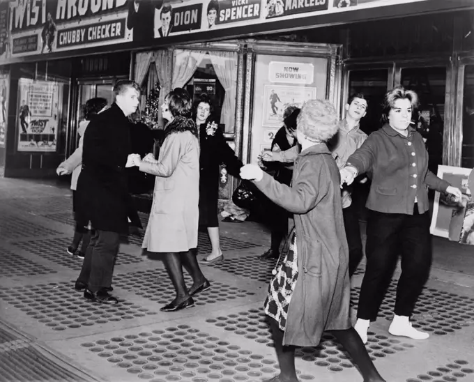 Teens dancing the 'Twist' outside the Brooklyn Fox Theatre before the premiere of the movie 'Twist Around the Clock'. 1961.