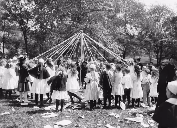 Children dancing around a Maypole, Central Park, New York City, 1905. The traditional spring ritual emerged from Germanic paganism of Iron Age or early Middle ages  (BSLOC_2018_3_89)