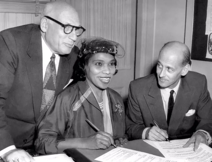 Singer Marian Anderson signs a contract with Metropolitan Opera representative Rudolf Bing (right). She was the first black performer to sing leading roles for the Met. Her manager, Sol Hurok (left), looks on, 1954