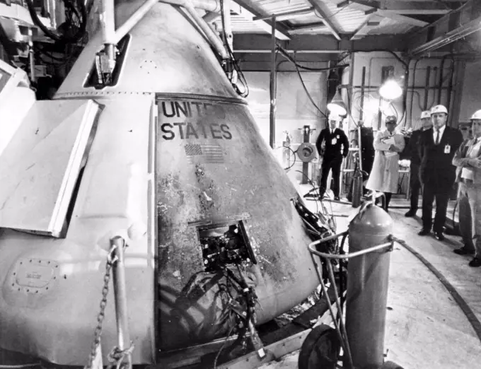 Technicians viewing the Apollo spacecraft where three flight crew members died during a launch simulation test, Cape Canaveral, Florida, 1967.