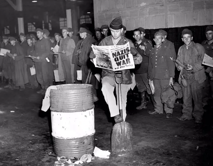 German prisoners of war in New York on the day Germany surrendered, ending the war in Europe. The newspaper headline reads: 'Nazis Quit War. V-E Day Today', May 8, 1945.