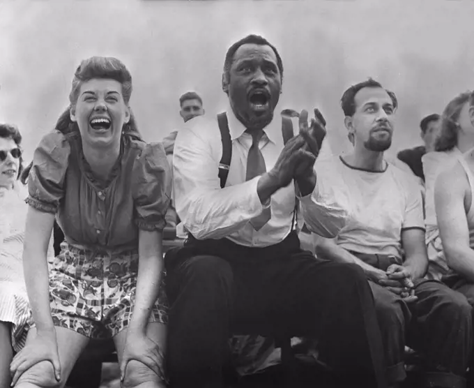 New York City, Paul Robeson (center), Jose Ferrer (right), watching softball with other members of Othello production, Central Park, circa 1943-1944.