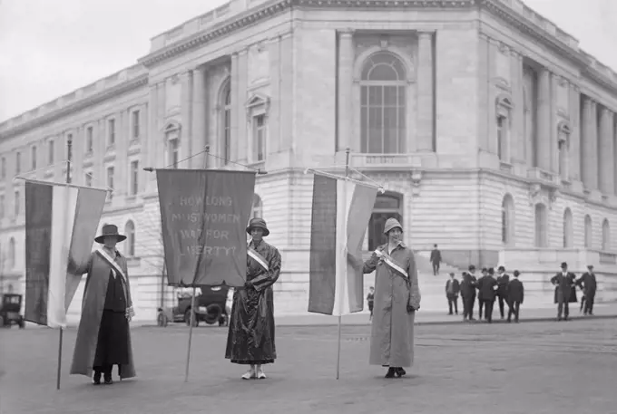 Suffragettes picketing the Senate Office Building in Washington in 1918. Left to right: Mildred Gilbert, Pauline Floyd, Vivian Pierce. They display a banner, 'How Long Must Women Wait for Liberty?'