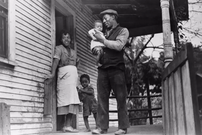 African American coal miner, his wife, and two of their children. The oldest child's bowed legs may be caused by rickets, a nutritional deficiency disease. Bertha Hill, West Virginia, 1938. Photo by Marion Post Wolcott.