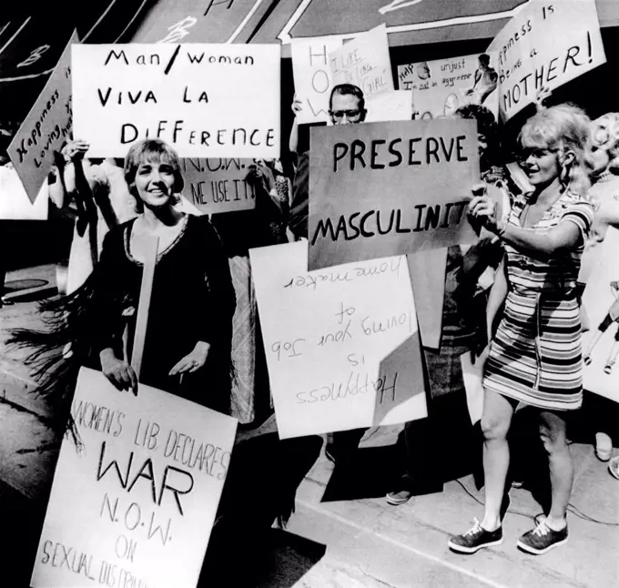 Anti-Women's Liberation protesters. They counter demonstrate with signs reading 'Viva la Difference', 'Preserve Masculinity', 'I like being a girl' and 'Happiness is being a mother.' A solitary feminist holds a sign, 'Womens liberation declares war now on sexual discrimination.' Aug. 26, 1970.