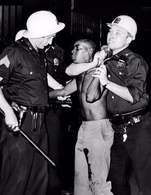 African American who has been shot in the leg, is restrained by New York City Police. He allegedly threw beer bottles at police on Lenox Avenue between 126 and 127th streets. The Harlem riots followed the July 16, 1964 killing of a 15-year-old boy by a policeman. July 20, 1964.
