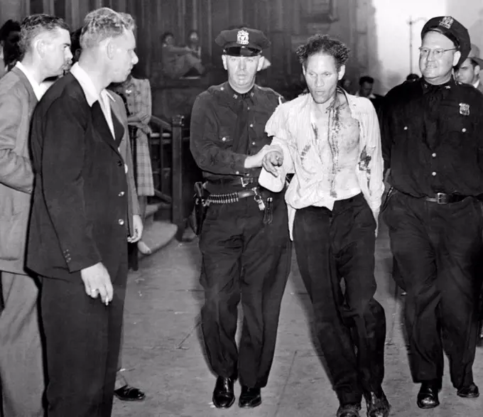 Race riot in New York City's Harlem section. They began when an African American soldier was shot when he intervened in a police beating of a women in the Braddock Hotel in Harlem. Photo shows a bloodied rioter, in police custody. August 2, 1943.