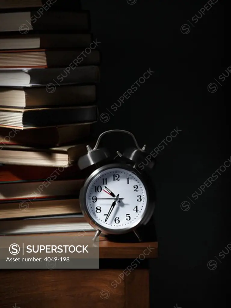 Close-up of an alarm clock with stack of books