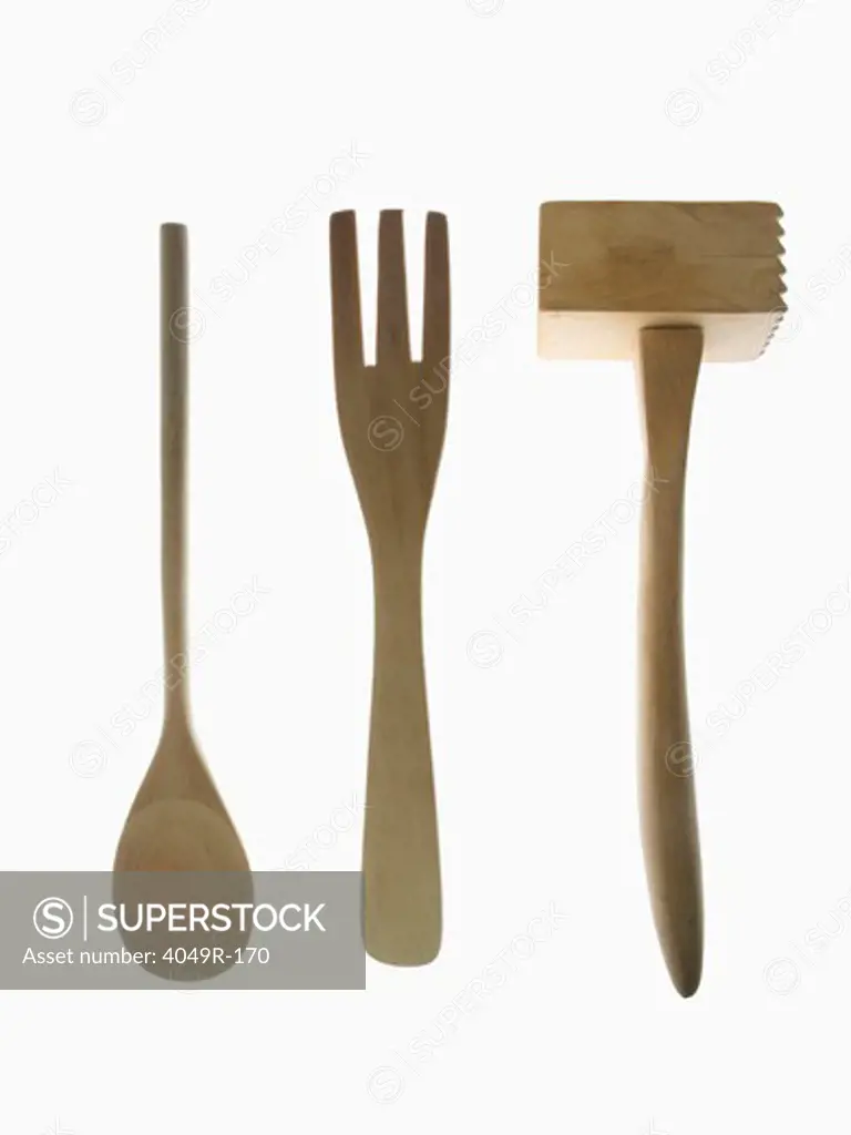Close-up of a wooden spoon with a fork and a meat tenderizer