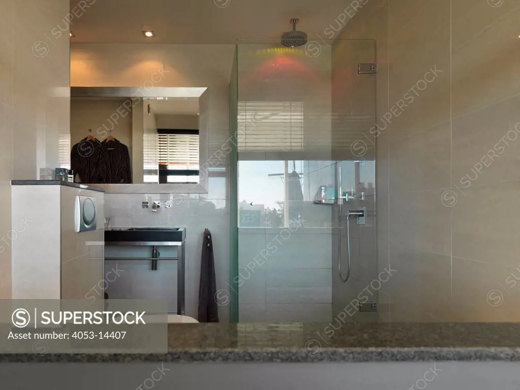 Tiled walls with shower cubicle by mirror over washbasin in the bathroom at home. Amsterdam, Netherlands. 08/10/2012