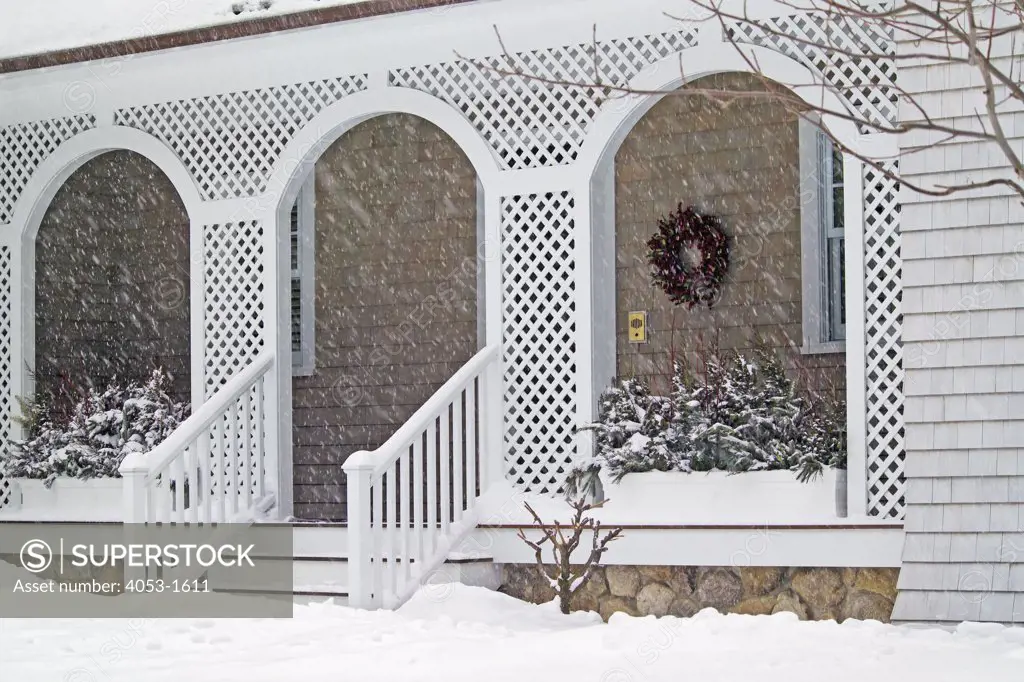 Front porch of shingle style home covered in snow