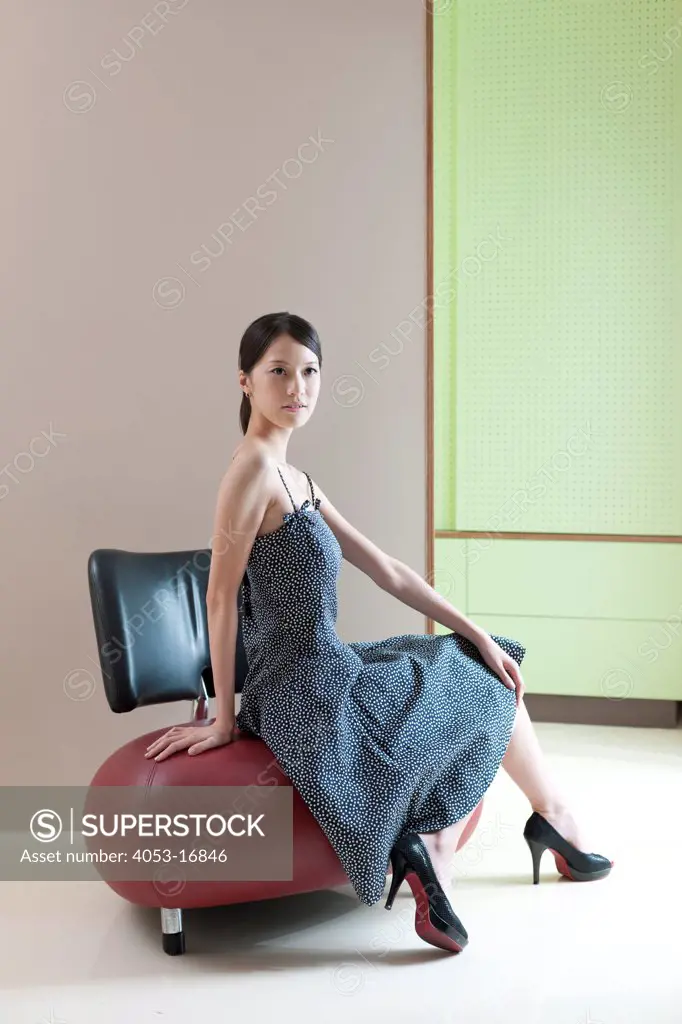 Portrait of a beautiful young woman sitting on modern chair at home, Taipei, Taiwan. 08/25/2010