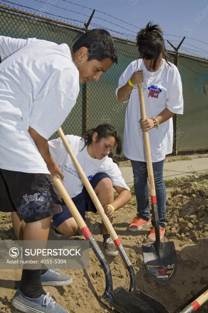 School Children dig hole at a tree planting along Mission Road in East Los Angeles, part of the Mayor's Million Trees LA Initiative. Los Angeles, California, USA