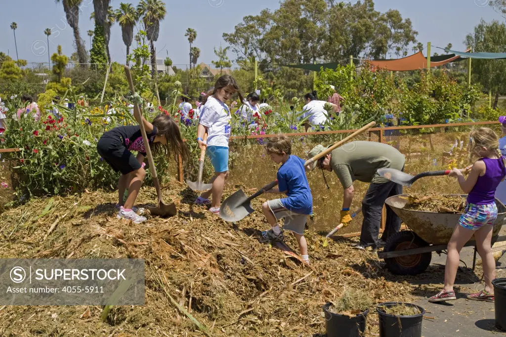 Shoveling compost. Students, parents and teachers work on the garden at the 24th Street School garden on Big Sunday, the largest annual citywide community service event in America, West Adams, Los Angeles, California, USA