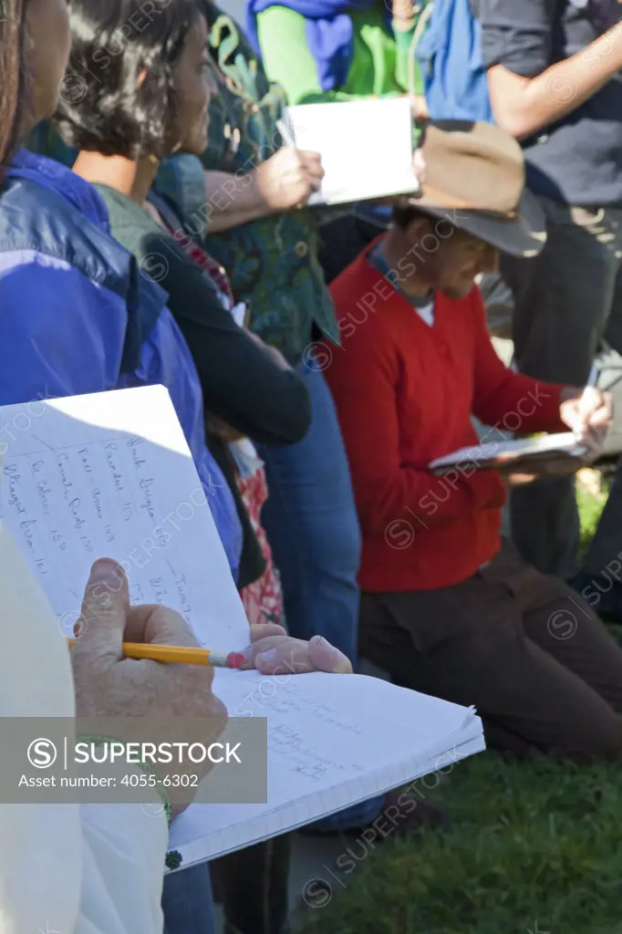 Taking notes during tour. Foraging for wild edibles in Los Angeles neighborhood Echo Park. Nance Klehm leads her Urbanforage guided walk showing and educating attendees about various greens, herbs and other edibles readily found along streets, lots and front yards. Los Angeles, California, USA