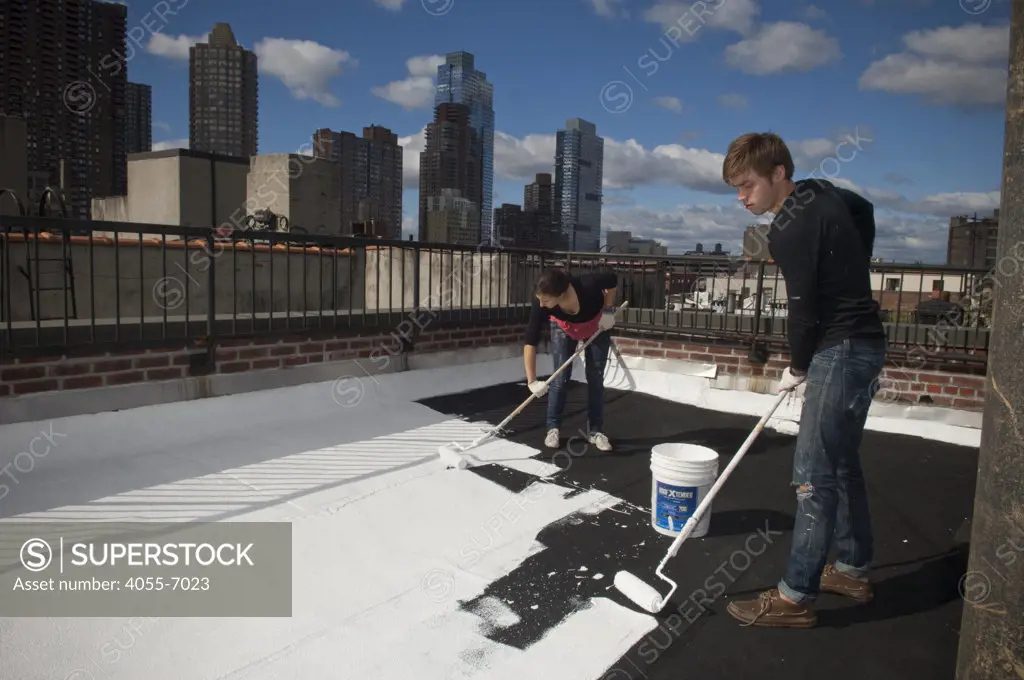 Austin Anderson, right, and Emma Podietz, left, college student volunteers,  paint a roof white near Times Square in New York on Saturday, October 16, 2010.