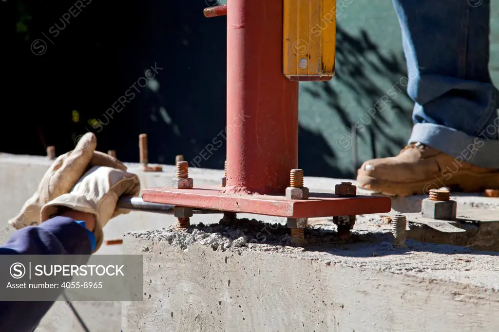 Vertical steel beam is leveled using four bolts spaced from the concrete foundation. Los Angles, California, USA