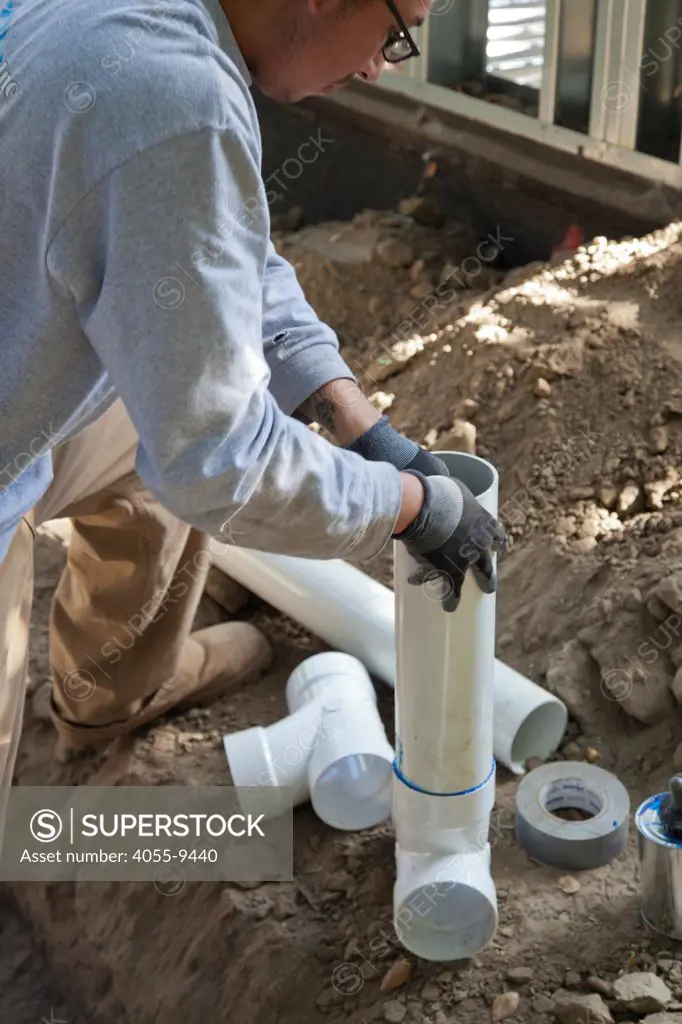 Poly Vinyl Chloride (PVC) Pipes being installed for rainwater harvesting system at new home construction. System is gravity based and relies on a 2% grade to carry captured water to cisterns or rain barrels in backyard. Los Angeles, California, USA