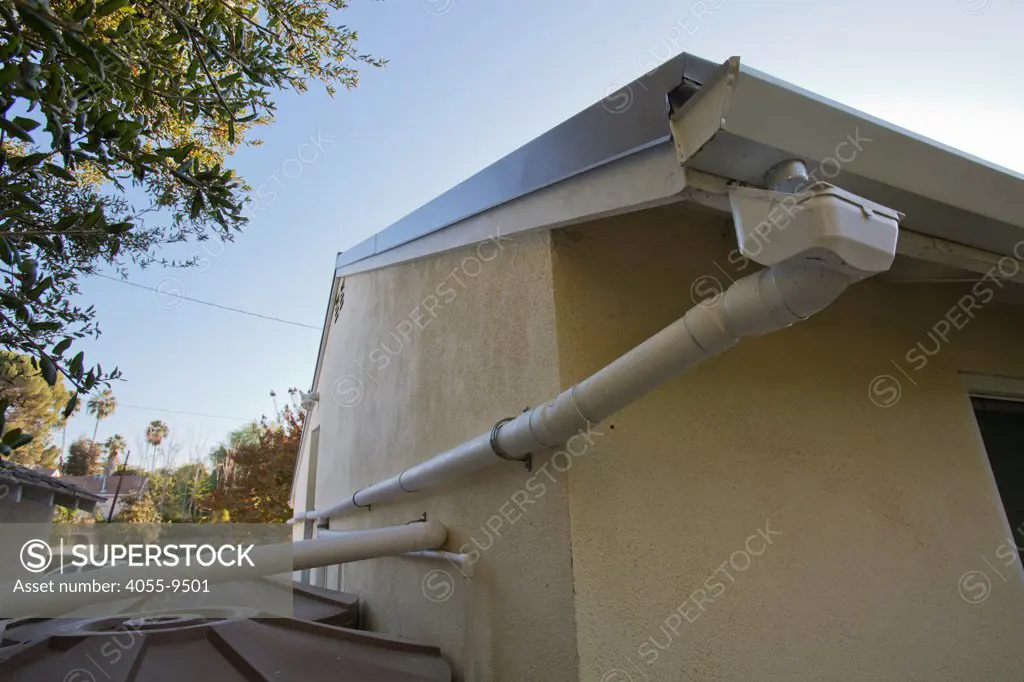 Drain pipes catch rain from metal roof for rainwater harvesting system on a Green home that is off the grid. Solar power and a rainwater harvesting system supply all the energy and water for this home in Los Angeles, California, USA