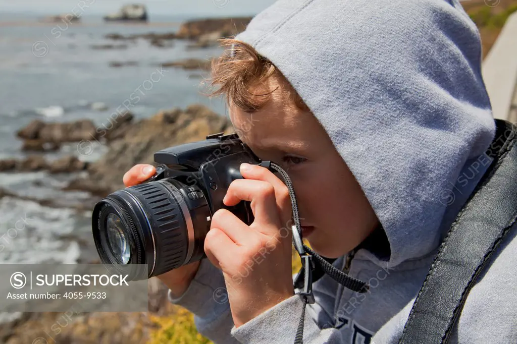 Young boy taking photos with a camera, San Simeon, San Luis Obispo County, California, USA (MR)