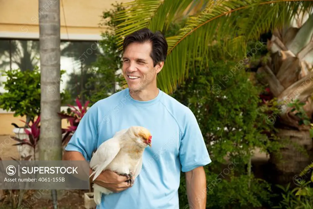 Mature man carrying a hen and smiling, Orlando, Florida, USA
