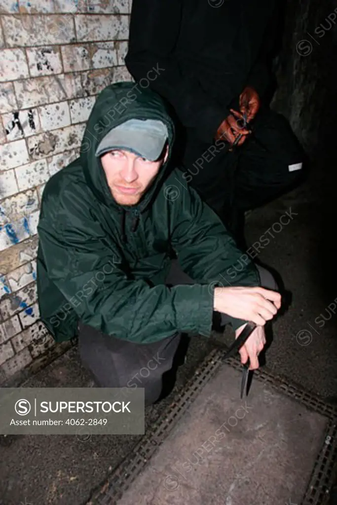 Two youths wearing a hoodie holding knives; on the street; London; UK 2006