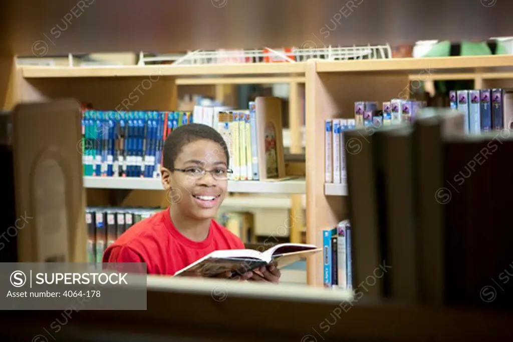 Middle school student reading a book in a library