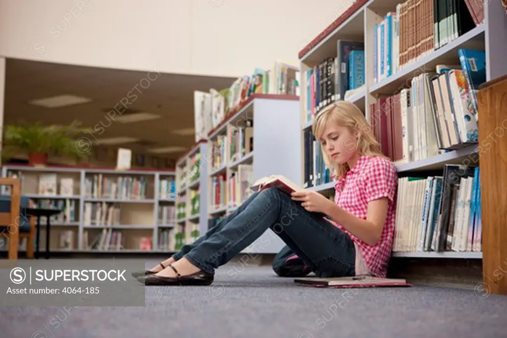 Middle school student reading in a library