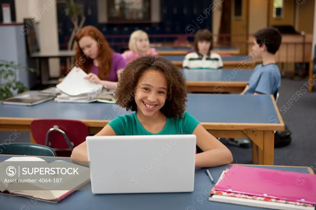 Middle school student using a laptop in a library