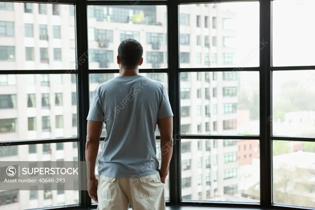 Man looking out on city from his loft apartment