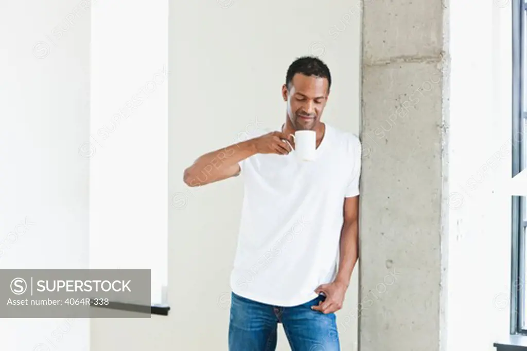 Man standing with coffee cup in loft apartment
