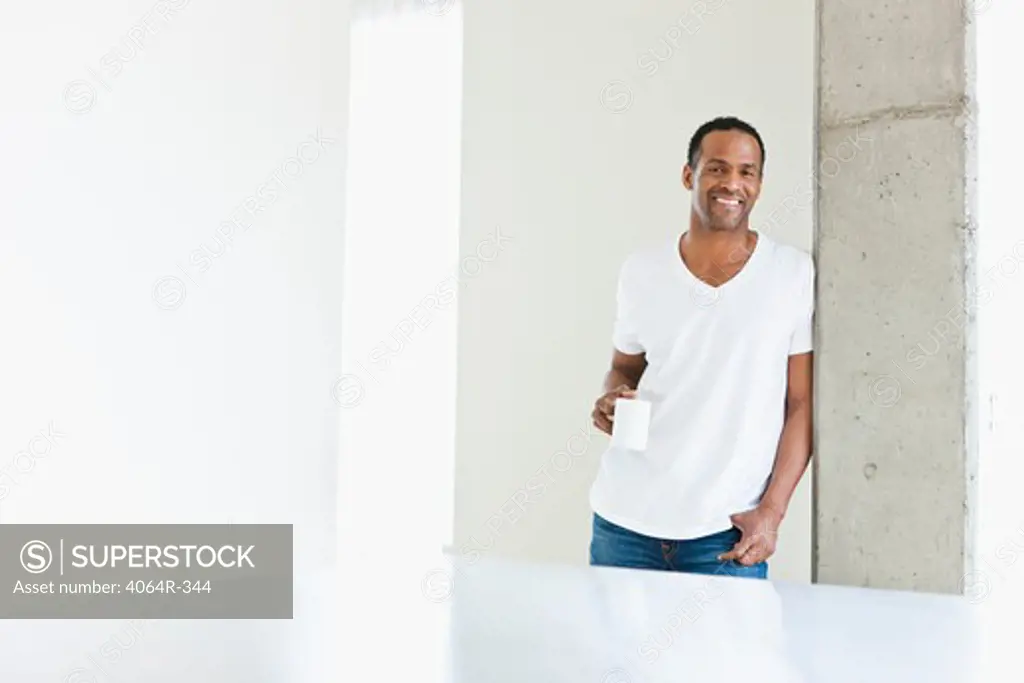 Man standing with coffee cup in loft apartment