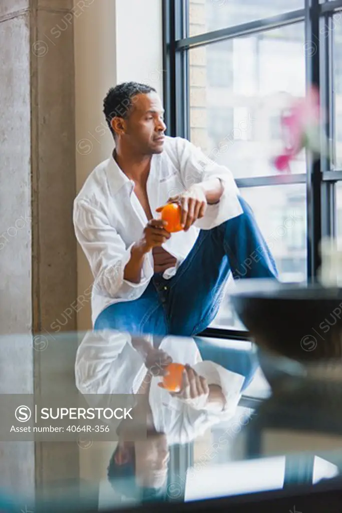 Man relaxing on window sill in loft apartment