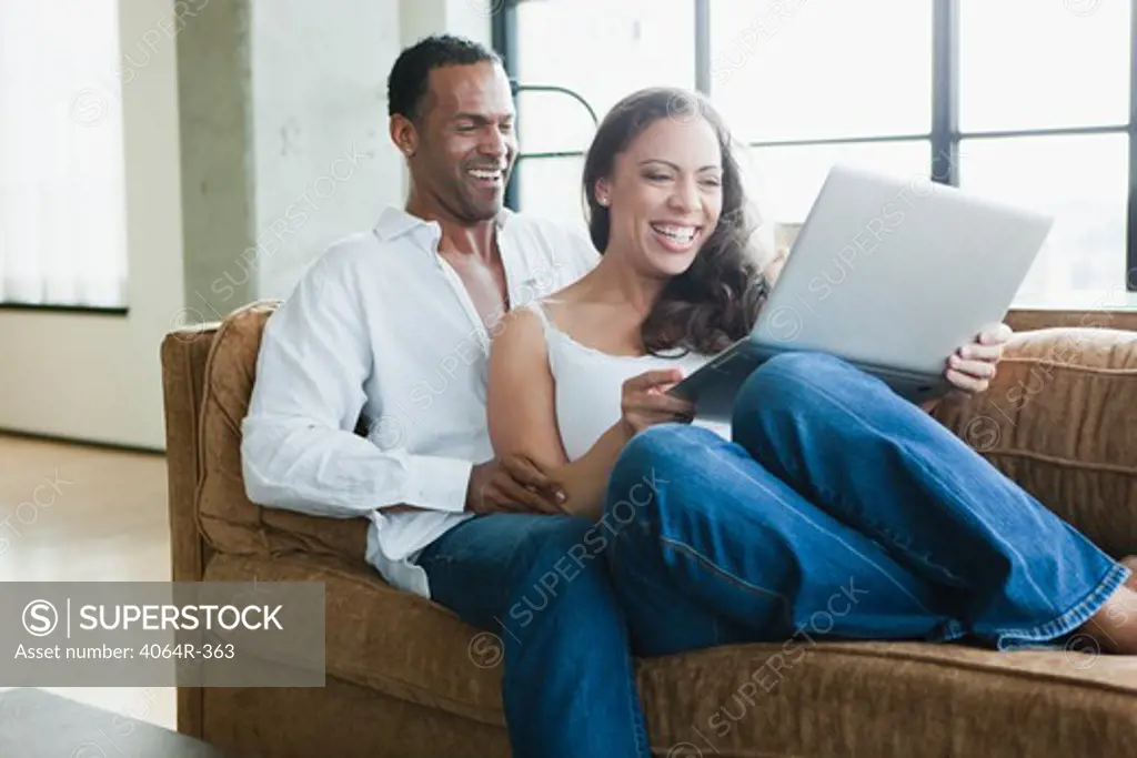 Couple sitting on couch and using laptop