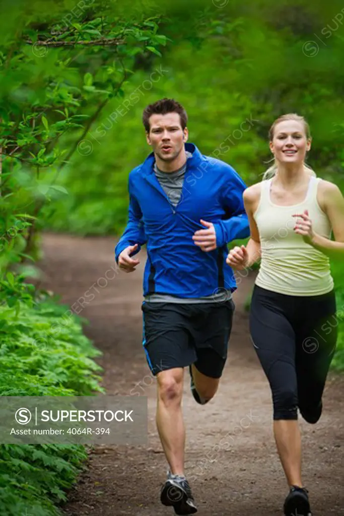 Portland, Oregon, USA, Couple running together on trail in forest