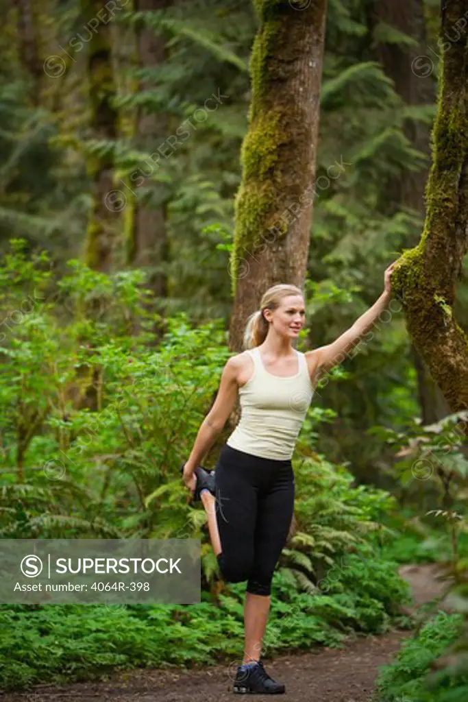 Portland, Oregon, USA, Woman stretching before run, on trail in forest
