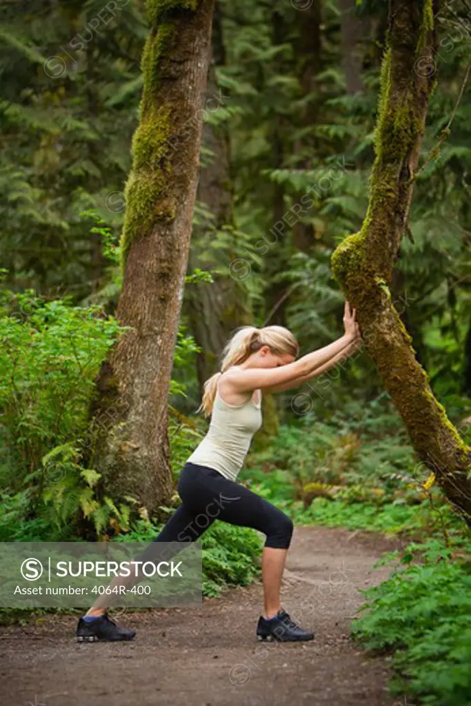 Portland, Oregon, USA, Woman stretching before run, on trail in forest