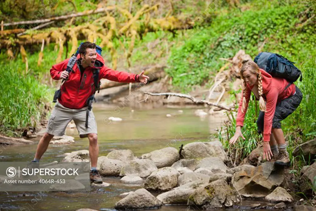 Portland, Oregon, USA, Man helping woman across creek