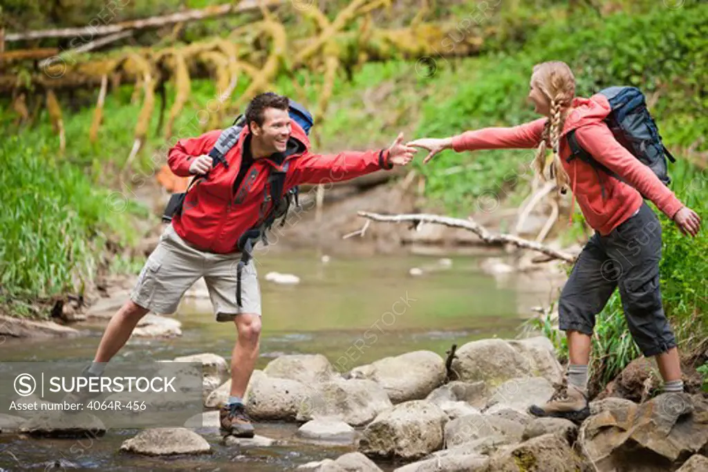 Portland, Oregon, USA, Man helping woman across creek