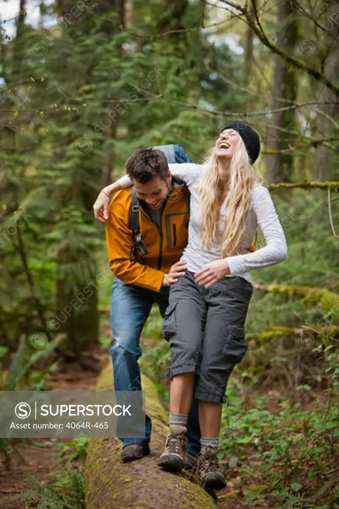 Portland, Oregon, USA, Couple walking along log in forest