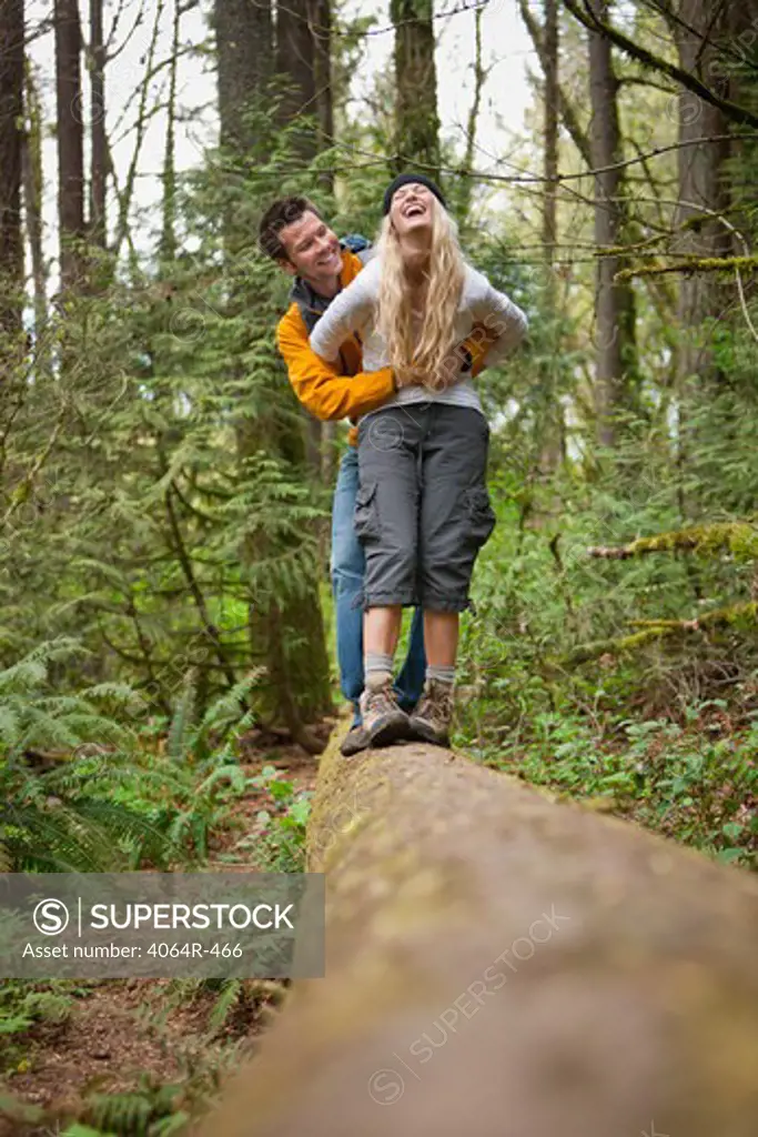Portland, Oregon, USA, Couple walking along log in forest
