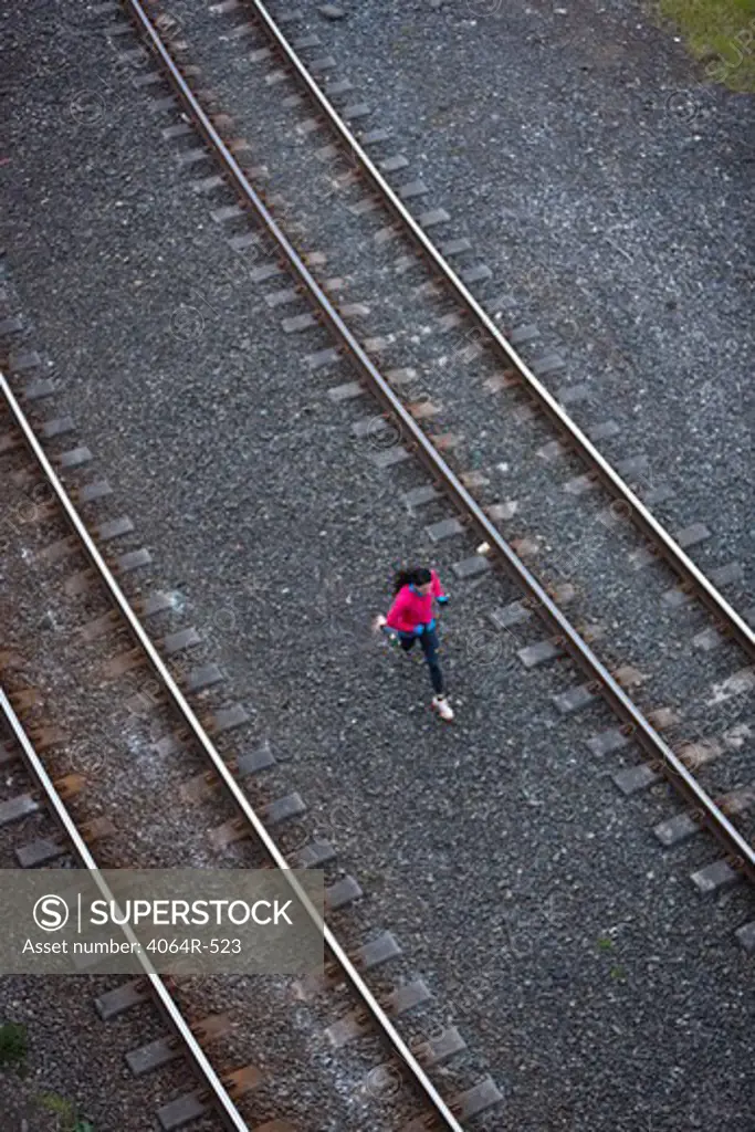 Woman running across railroad tracks