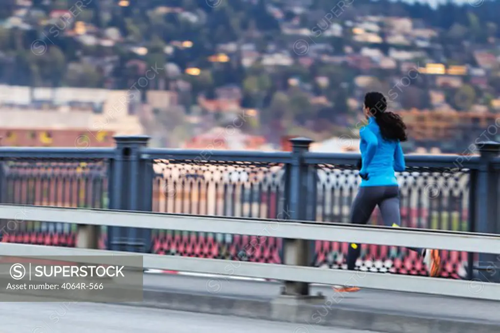Young woman running along bridge