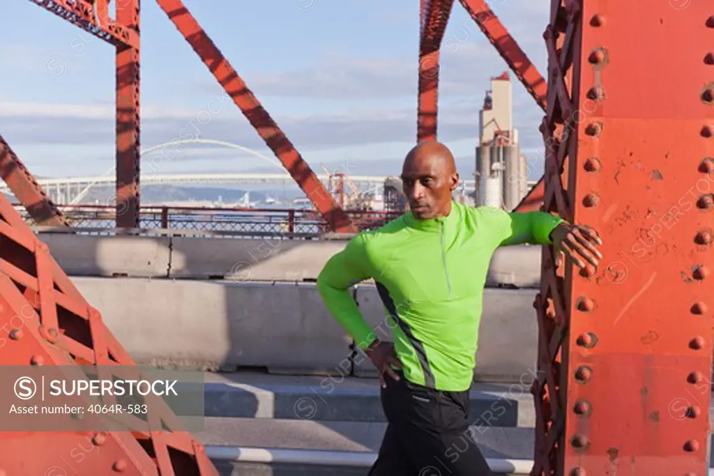 Male jogger, stretching on bridge