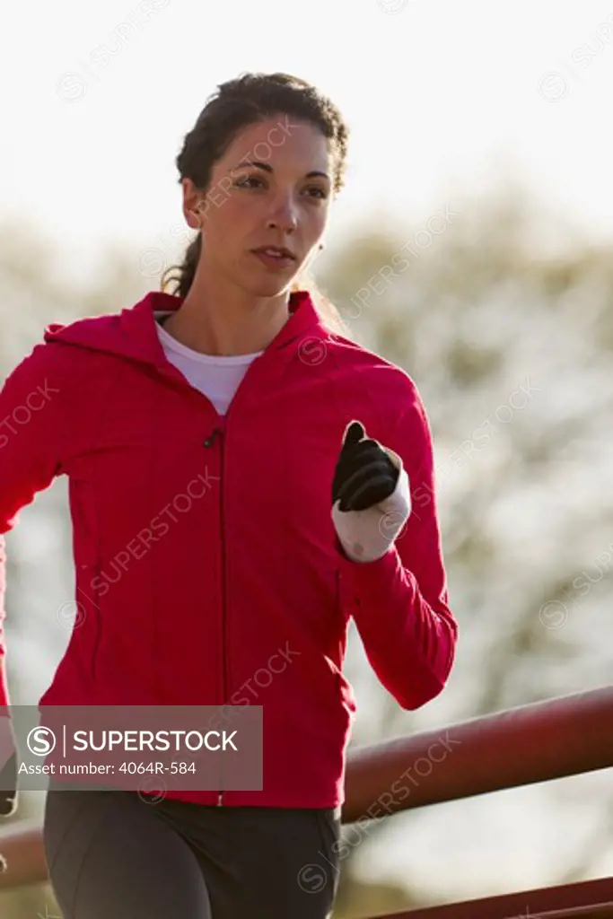 Young woman running along bridge