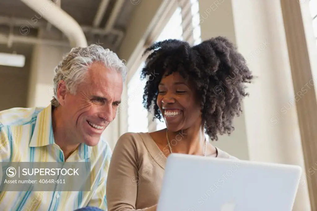Businessman and woman using laptop in office