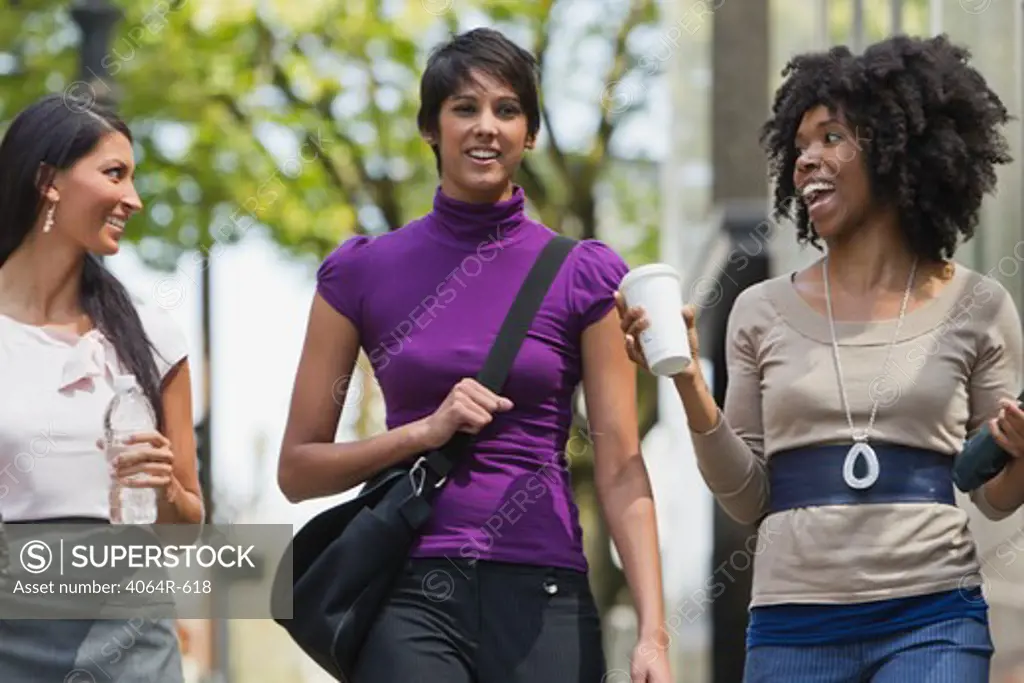 Three businesswomen walking in street downtown