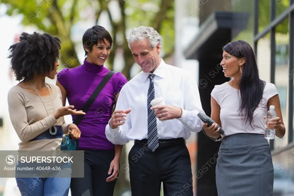 Three businesswomen walking outside office with businessman
