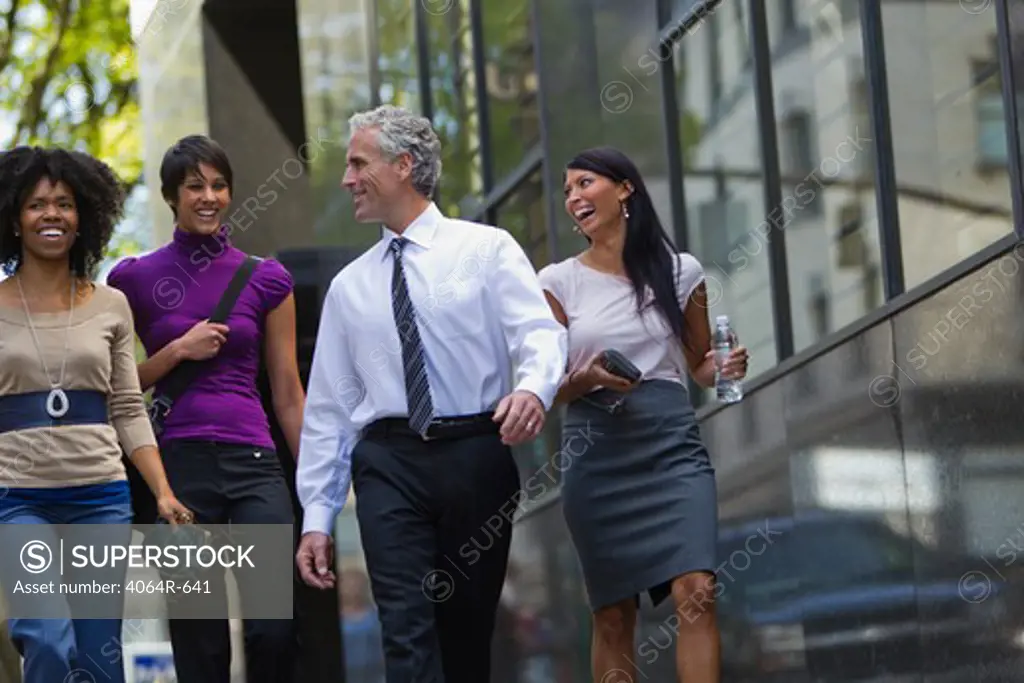 Three businesswomen walking outside office with businessman